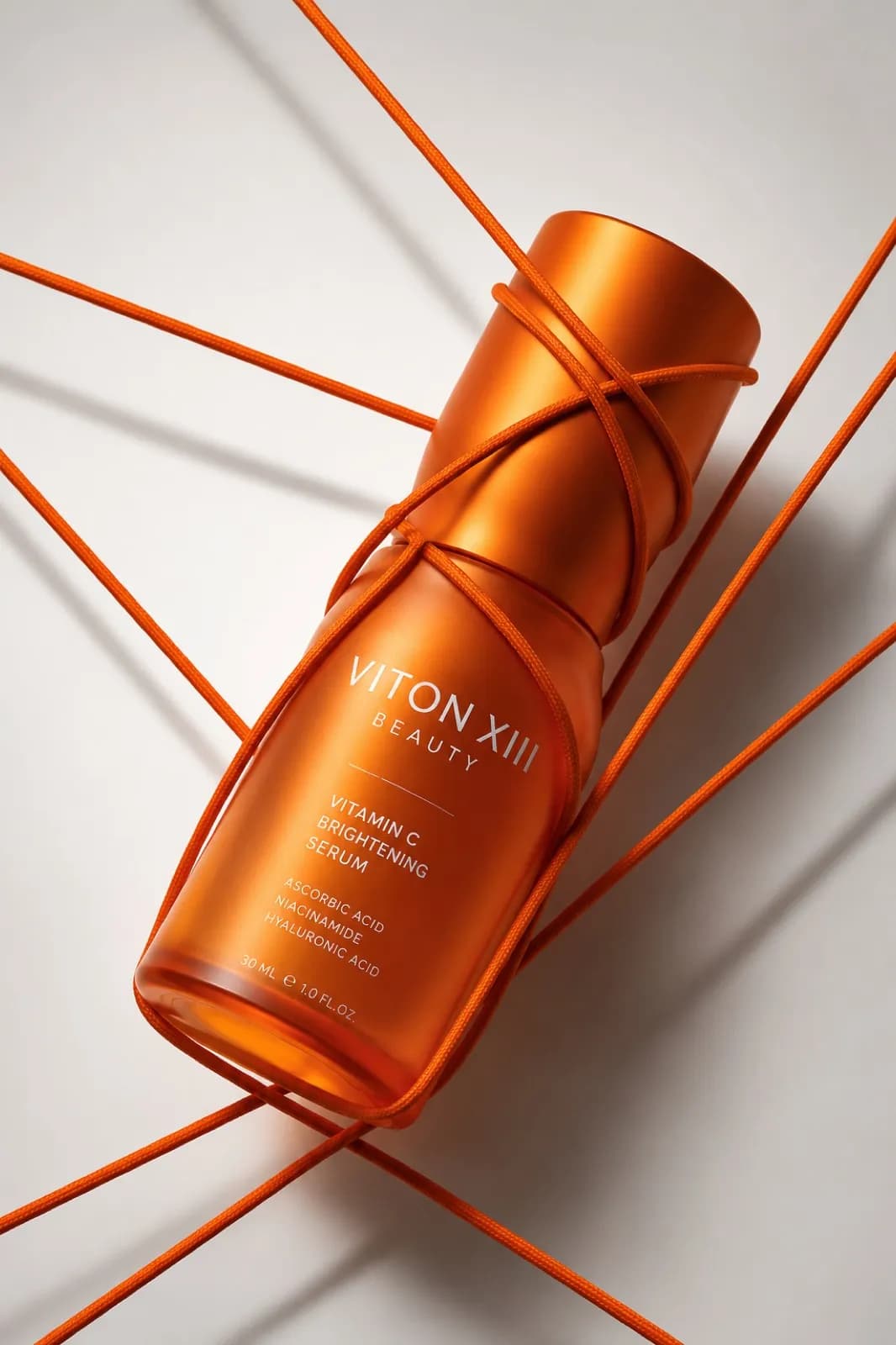AI-generated key visual: an orange VITON XIII BEAUTY Vitamin C serum bottle wrapped in orange cord that crosses a light background