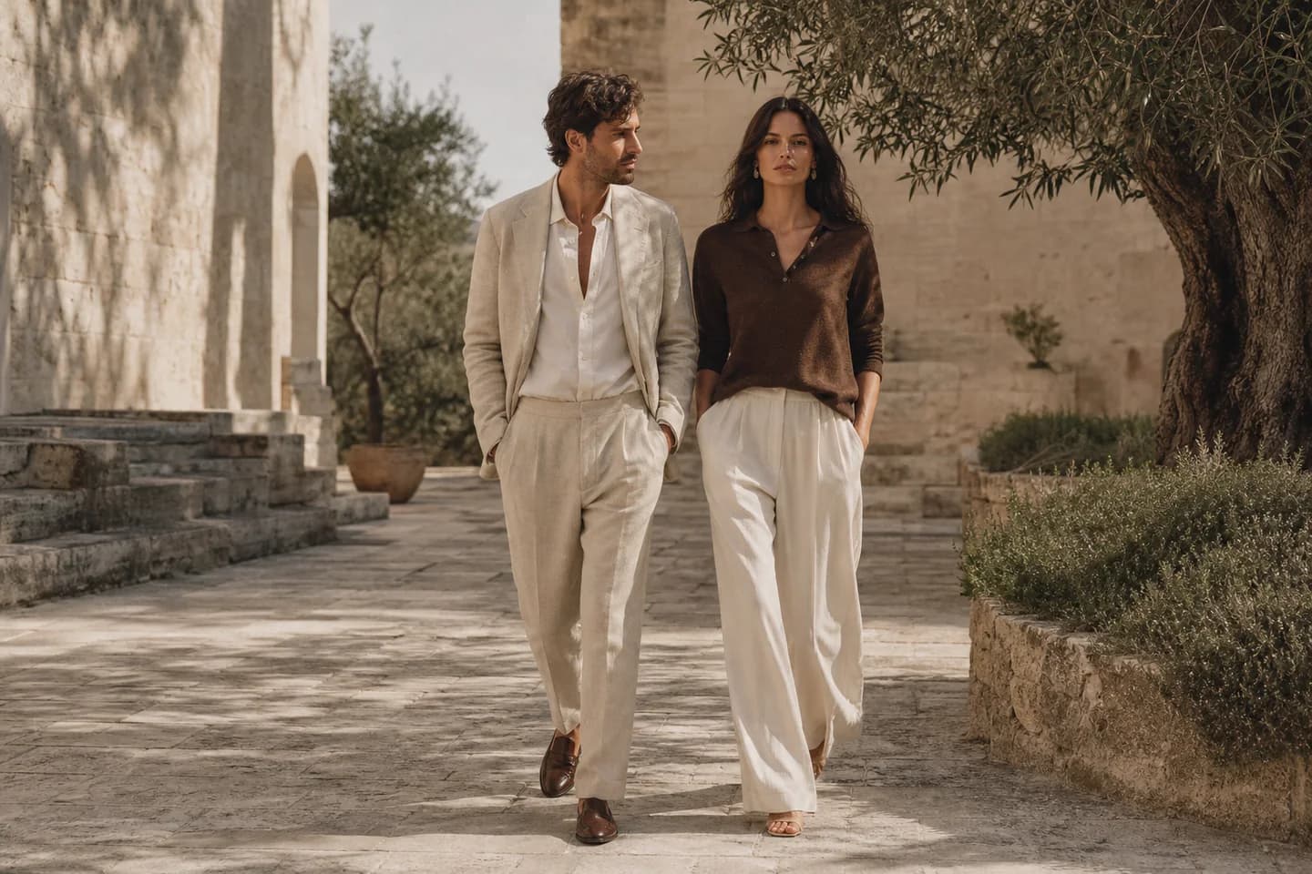 AI-generated image: a man in a light beige suit and a woman in a brown polo and cream trousers walk through a sunlit stone courtyard