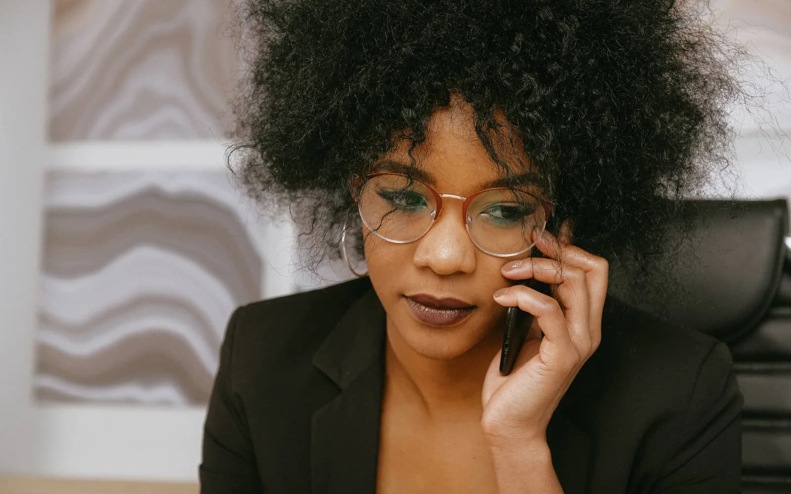 Une professionnelle en blazer noir répond à un appel téléphonique à son bureau