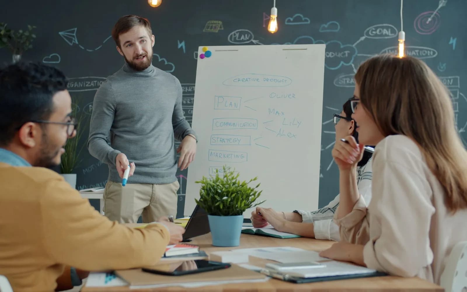 Un equipo comenta un plan junto a una pizarra con notas sobre objetivos, canales y estrategia